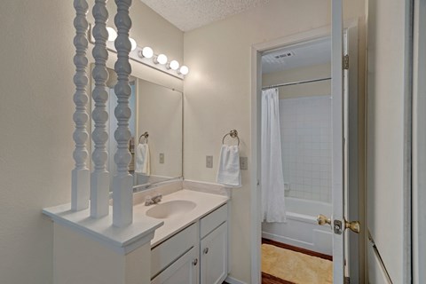 A bathroom with a sink, mirror, and towel rack.