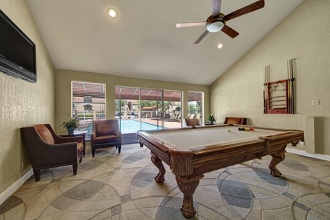 A room with a pool table and a television.
