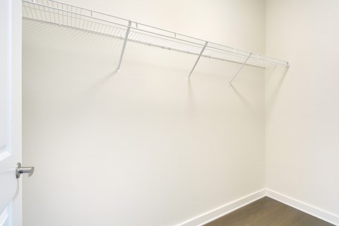 A large walk-in closet with a white door and a white shelves.