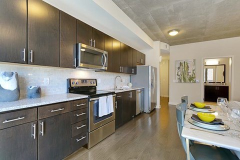 A modern kitchen with dark wood cabinets and stainless steel appliances.