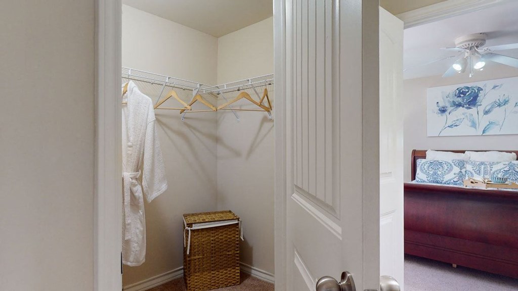 a closet with a dresser and a bed in it