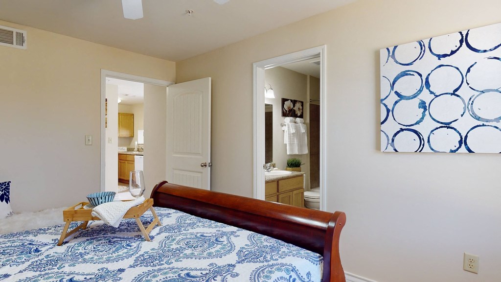 a bedroom with a bed and a bathroom in the background