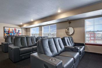 a theater room with leather couches and chairs