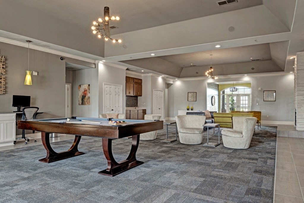 Modern recreation room here at Lincoln at Central Park Apartment Homes with a pool table, plush seating, and contemporary lighting. Warm tones, stylish decor, and inviting atmosphere suggest relaxation.