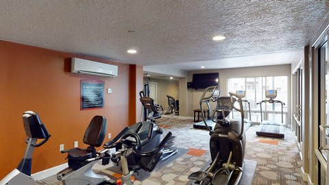 A gym with orange walls and a variety of exercise equipment.