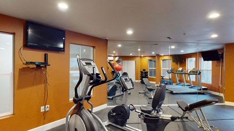 A gym with treadmills, exercise bikes, and a television.