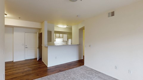 A room with a white wall and a grey carpet.