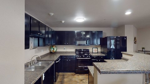 A modern kitchen with black cabinets and granite countertops.