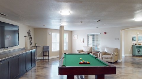 A pool table with a green cloth and white balls is in the center of the room.