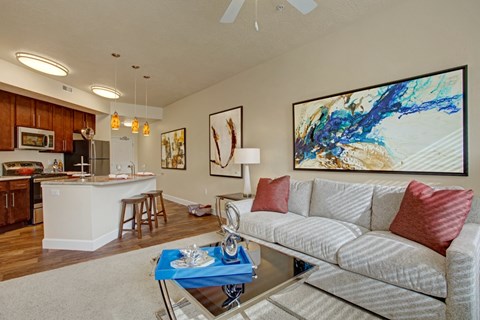 A living room with a grey couch and a painting on the wall.