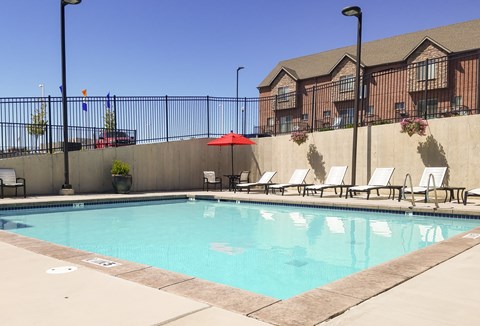 A pool with chairs and umbrellas in front of a building.