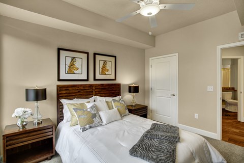 A bedroom with a bed, two lamps, and two framed pictures on the wall.