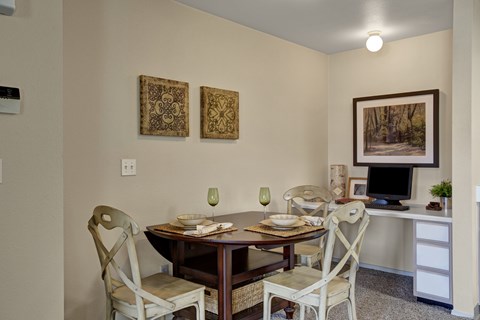A dining room with a table set for two and two chairs.