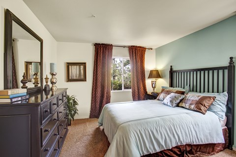 A bedroom with a large bed and a dresser with a mirror.