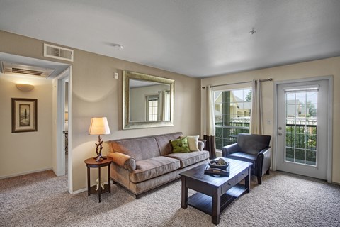 A living room with a couch, a coffee table, and a mirror.
