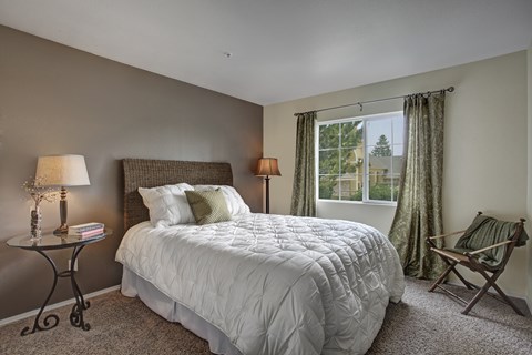 A bedroom with a large bed and a chair.