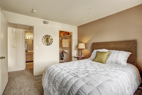 A bedroom with a large bed and a mirror on the wall.