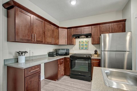 A kitchen with brown cabinets and a stainless steel refrigerator.