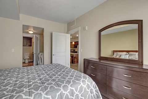 A bedroom with a bed, dresser and mirror.