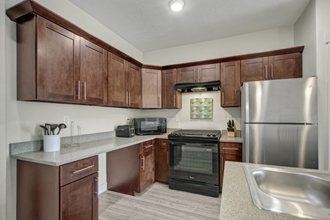 A kitchen with brown cabinets and a stainless steel refrigerator.
