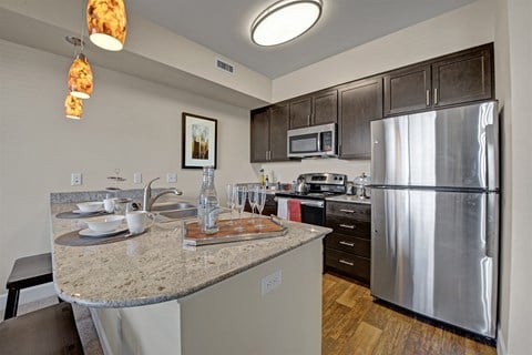 A kitchen with a granite counter top and stainless steel appliances.
