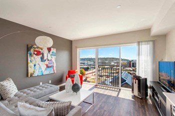 A spacious living room with large windows and a sliding glass door leadnig out to the Juliet balcony Vive Living Room - Photo Gallery 6