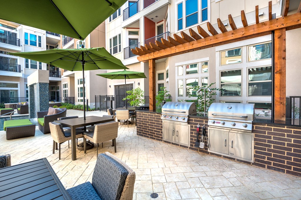 a patio with a grill and tables with umbrellas