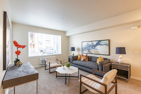 A living room with a grey couch, a coffee table, and a painting on the wall.