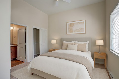 A bedroom with a large bed and two lamps.