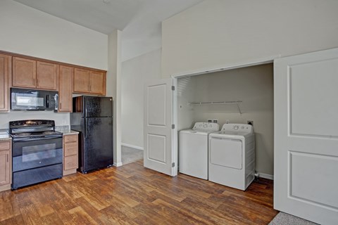 A kitchen with wooden cabinets and a black refrigerator.