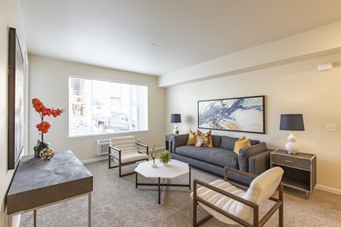 A living room with a grey couch, a coffee table, and a painting on the wall.