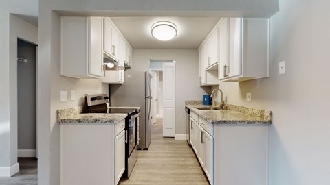A kitchen with white cabinets and granite countertops.