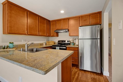 A kitchen with a granite counter top and wooden cabinets.