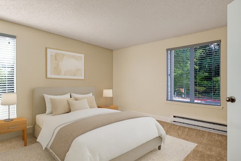 A bedroom with a large bed and a window with blinds.