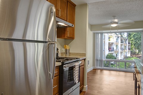 A kitchen with a stainless steel refrigerator and wooden cabinets.