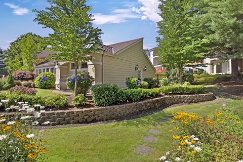 A yellow house with a stone wall and a garden in front.
