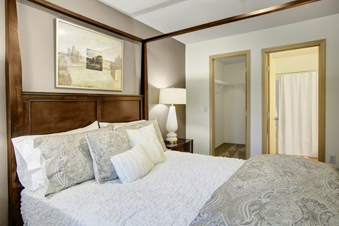 A bedroom with a large bed and a painting on the wall.