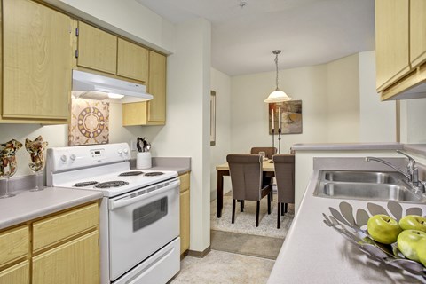 A kitchen with a stove, sink, and dining table.