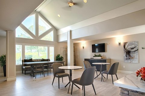 A modern dining room with a glass table and grey chairs.