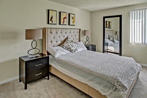 A bedroom with a large bed and a nightstand with a lamp.