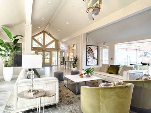 A living room with a white sofa, a yellow armchair, and a glass table with a lamp on it.