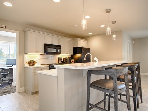 A kitchen with a white counter and bar stools.