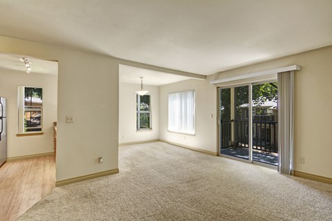 A spacious room with a sliding glass door leading to a balcony.