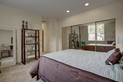 A bedroom with a large bed and a mirrored closet door.