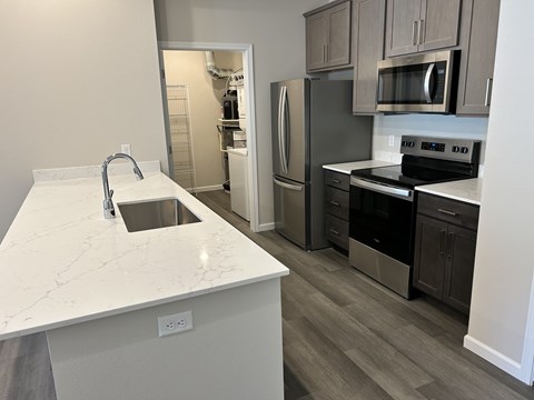 A kitchen with a white counter top and a refrigerator.
