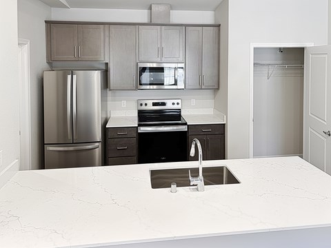 A kitchen with a white counter top and stainless steel appliances.