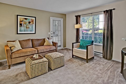 A living room with a brown couch, a green chair, and a painting on the wall.
