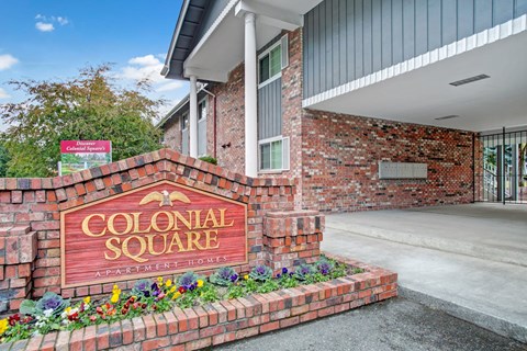 A sign that says Colonial Square in front of a building.