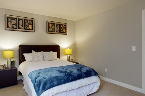 A bedroom with a large bed and two lamps on either side of the bed.