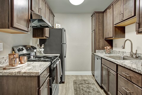 A kitchen with a black refrigerator and brown cabinets.